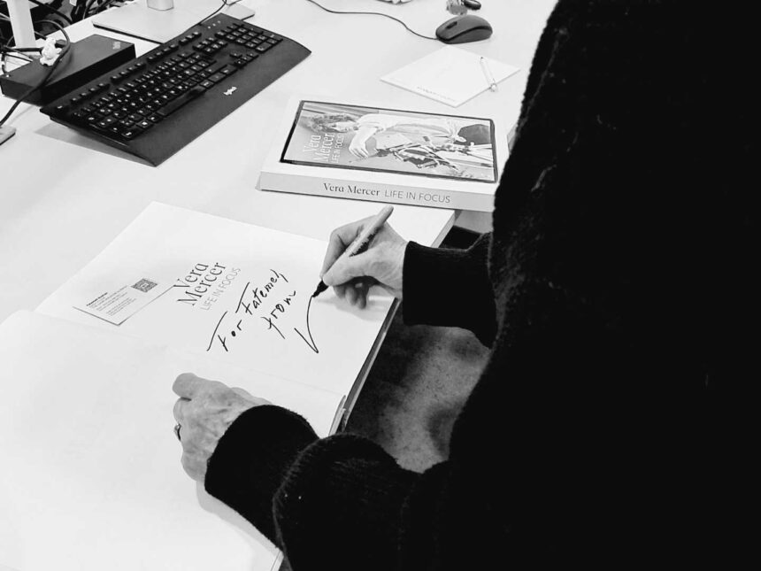 Artist Vera Mercer signing a copy of her book, 