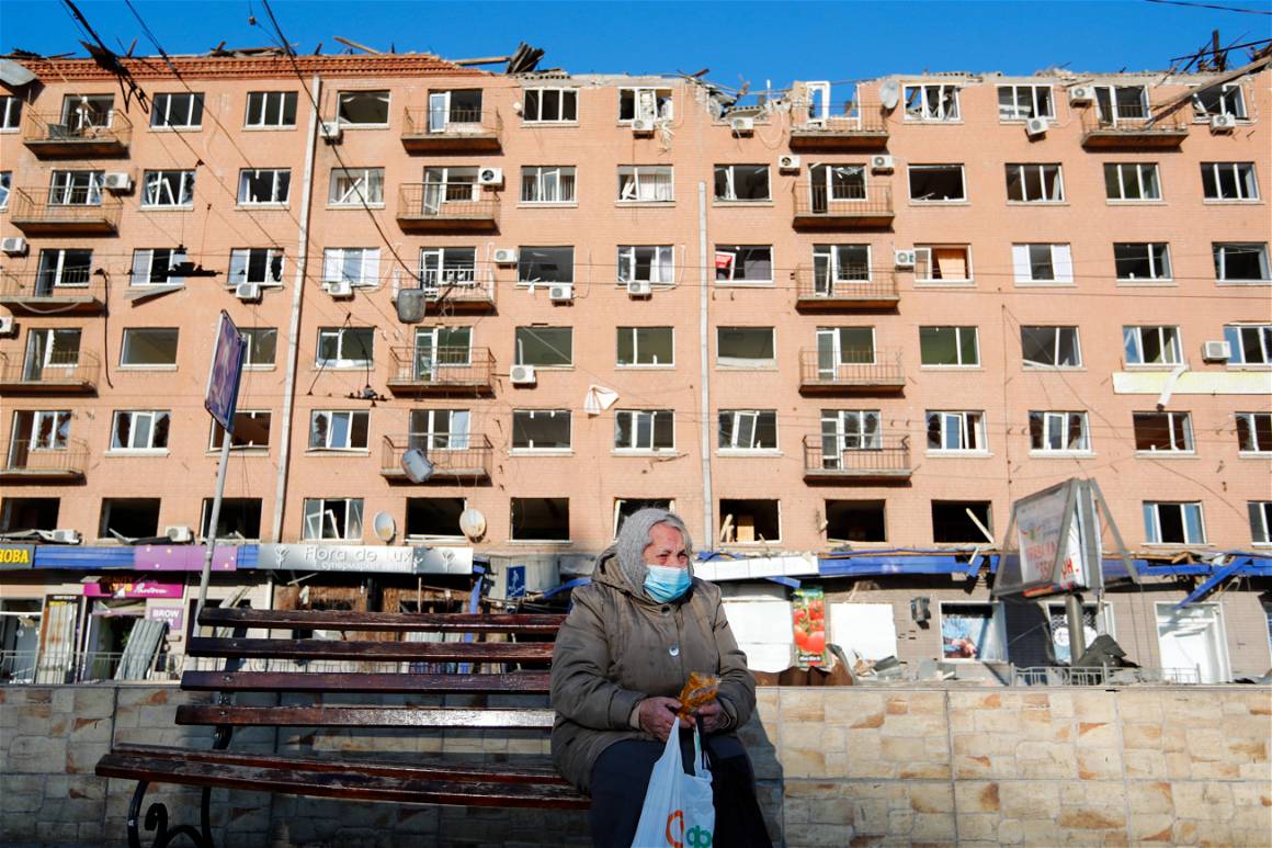 IMAGO / NurPhoto / Ceng Shou Yi. 19 March, 2022, Kyiv Ukraine. A elderly Ukrainian woman who says her family members have passed away in an attack by Russia, sits on a chair in front of a damaged apartment by missile attacks.