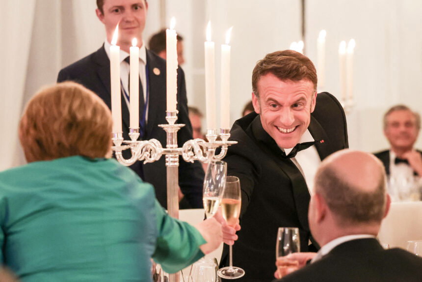 Macron toasts his glass of champagne with Angela Merkel