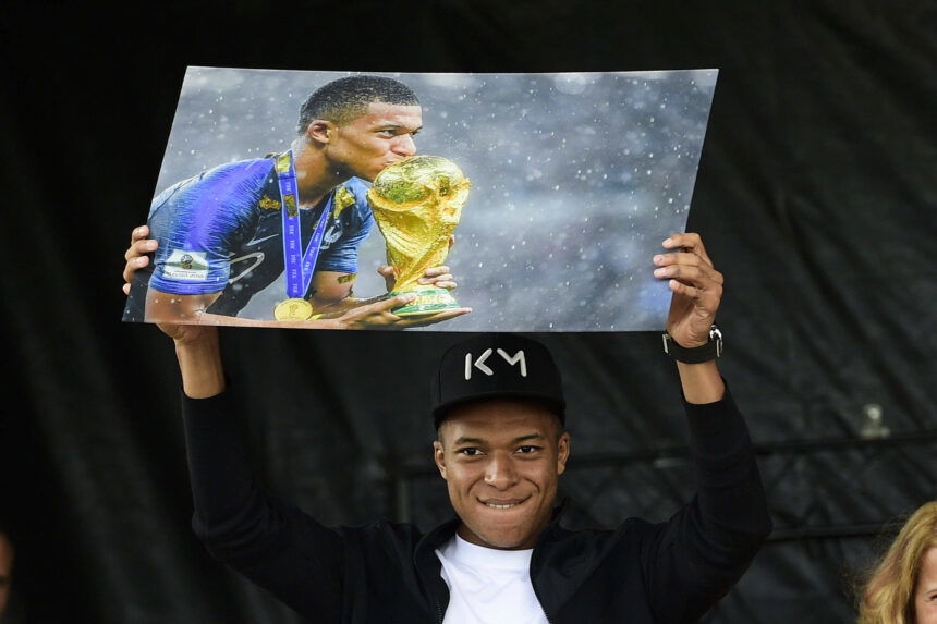 Kylian Mbappé holds a framed image of the 2018 World Cup trophy during his return to Bondy, France.
